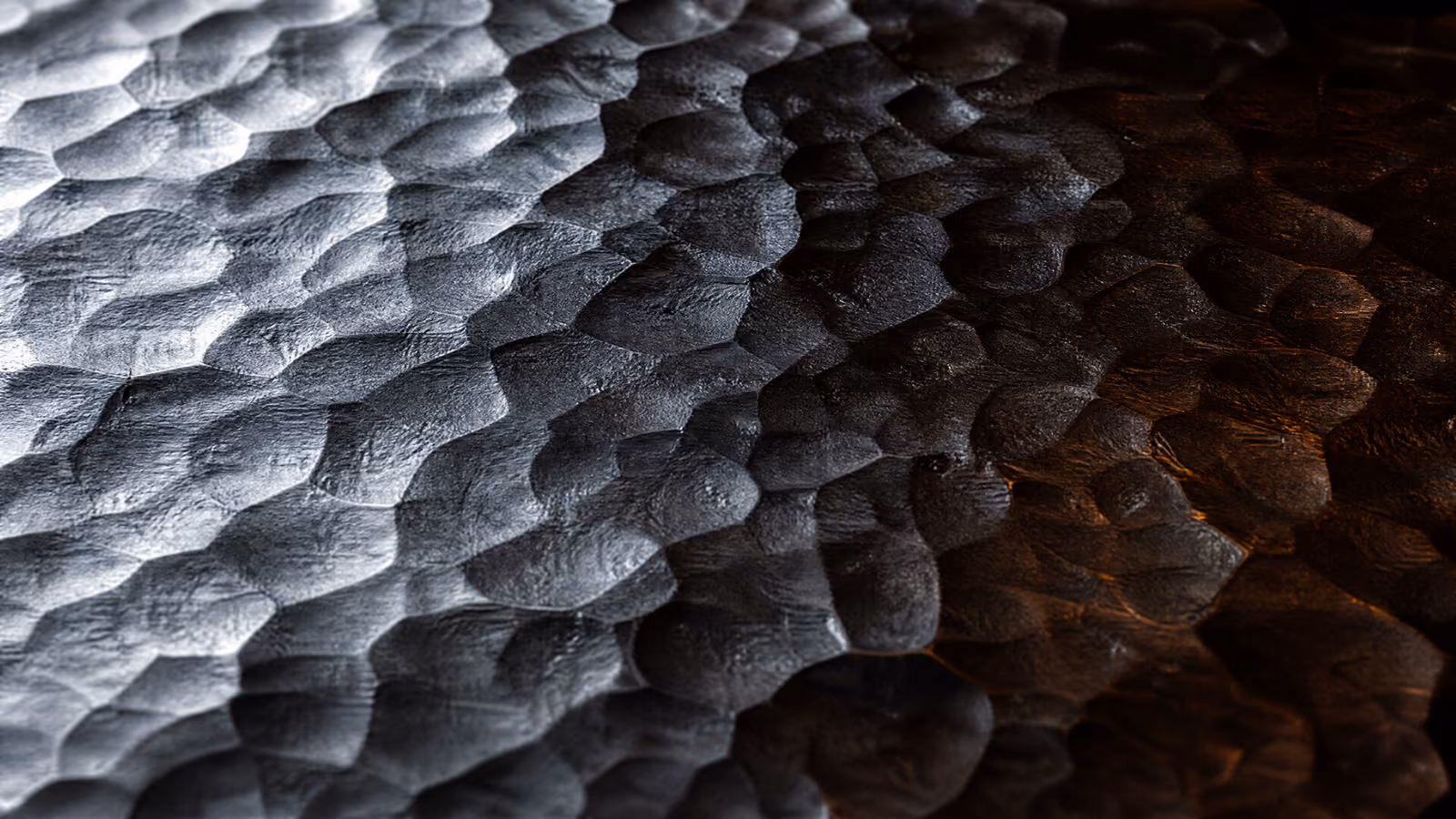 Hammered steel under hard raking light, every facet catching an edge.